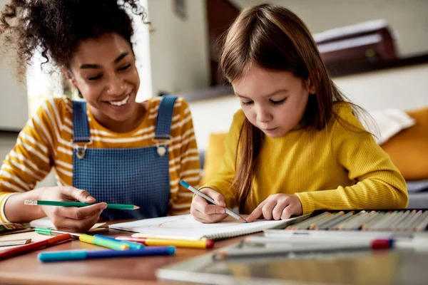 Small Steps. Caucasian little girl spending time with african american baby sitter. Kid is drawing, learning how to draw — Stock Photo, Image