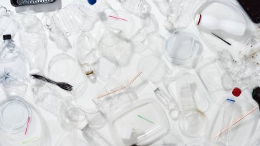 Kullanılmış plastik şişeler, kaplar, çatallar, kaşıklar, yumurta ambalajları, beyaz arka planda kapaklar