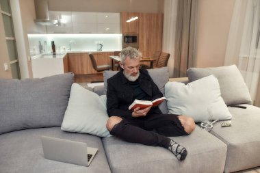 Rahat ol. Orta yaşlı sakallı bir adam kanepede otururken kitap okuyor. Yanında duran plastik torba içinde nargile ya da cam su borusu ve tomurcukları. Esrar ve ot yasallaştırma kavramı