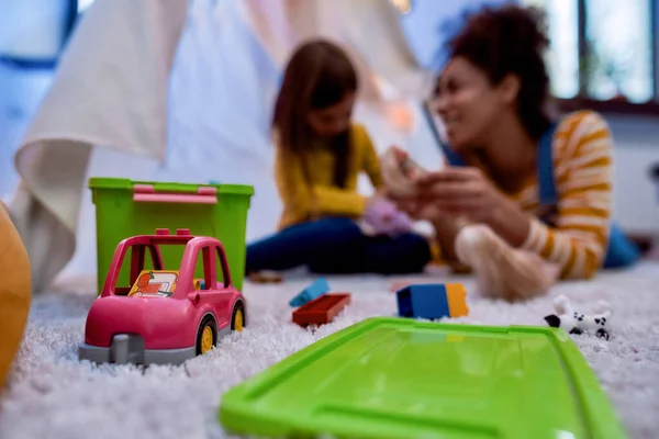 El cuidado de niños importa. Mujer afroamericana niñera entretenido caucásico linda niña. Están jugando con muñecas juntas. — Foto de Stock