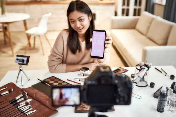 Ti piacera '. Bellezza blogger donna riprese, pubblicità app sulla macchina fotografica, tenendo smartphone. Trucco influencer ragazza asiatica registrazione cosmetici recensione del prodotto a casa — Foto Stock