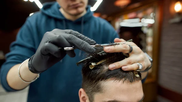Moderner Haarschnitt. Nahaufnahme eines professionellen männlichen Friseurs, der für seinen Kunden eine Frisur schneidet und mit Schere und Haarkamm arbeitet — Stockfoto