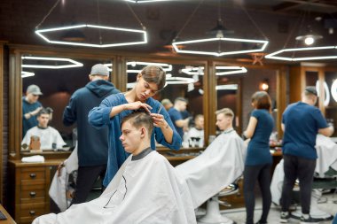 Profesyonel berber kız ya da kadın kuaförün müşteriye hizmet edişinin yan görüntüsü, genç beyaz adam için modaya uygun saç kesimi yapması. Modern berber dükkanını ziyaret eden adam