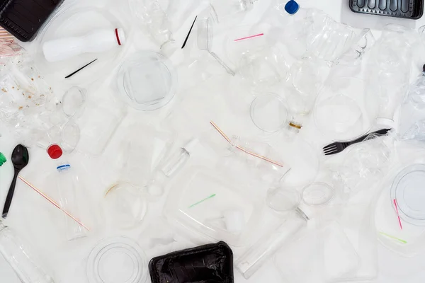 Flatlay composition with used plastic bottles, containers, forks, spoons, egg packaging, caps over white background — Stock Photo, Image