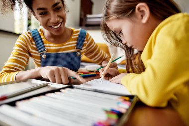Bebek bakıcısı. Kafkasyalı küçük kızın Afrikalı Amerikalı dadısıyla vakit geçirmesine yakın çekim. Çocuk kalem kullanarak mektup yazmayı öğreniyor.