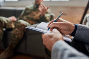 Notlar. Terapi seansı sırasında askerlerle iletişim kurarken not alan psikoloğun ellerini kapatın. Depresyon geçiren asker, psikolojik travma. Travma Sonrası Stres