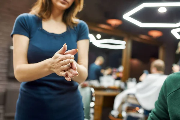 Cosmética para el cabello. Primer plano de una peluquera o peluquera usando cera o gel para peinar el cabello mientras trabaja en una peluquería o peluquería — Foto de Stock