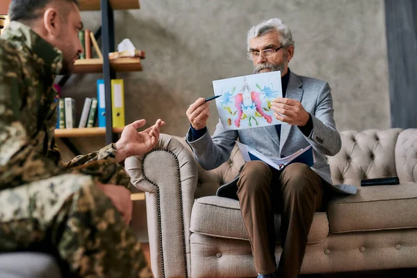 Volwassen psycholoog houdt foto met inktvlek, Rorschach Inkblot voor militaire man tijdens therapie sessie. Soldaat lijdt aan depressie, psychologisch trauma. PTSS-concept — Stockfoto