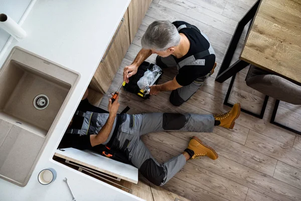 Tamir servisi için en iyisi. İş arkadaşı alet, tornavida ve alet kutusundan İngiliz anahtarı getirirken, su tesisatçısı ya da üniformalı bir tamirci lavabo borusunu tamir ediyordu. Onarım servisi kavramı