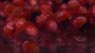 Küçük kırmızı mücevherler. Siyah arka planda düşen ve yuvarlanan nar tohumlarının süper yavaş çekimi. Nar tanecikleri 4K videosunu kapatır. Sağlıklı beslenme, meyve konsepti.