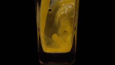 Meyve suyunu tat. Portakal suyunu şeffaf bir bardağa doldururken çekilen süper yavaş çekim siyah arka plana karşı. Kapatın. Sağlıklı içecek, vitaminler, meyve konsepti