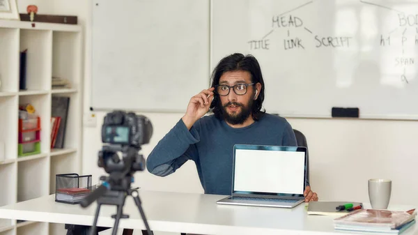 Молодой профессиональный программист записывает видео учебник для своего блога о профессиональном цифровом оборудовании. Смотреть в камеру и настраивать очки — стоковое фото