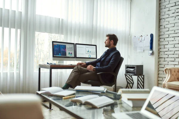 Working with statistical data. Young businessman, financial analyst sitting in the modern office, looking at graphs and charts on pc screen and analyzing online report — Stock Photo, Image