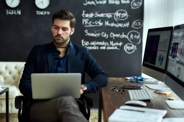 Analyzing statistical data. Portrait of a young concentrated businessman, financial analyst or sales manager sitting at his workplace in the office and working on laptop — Stock Photo, Image