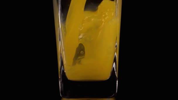 Чистый сок. Супер замедленная съемка заливки апельсинового сока в прозрачный стакан на черном фоне. Закрывай. Здоровый напиток, витамины, фрукты — стоковое видео
