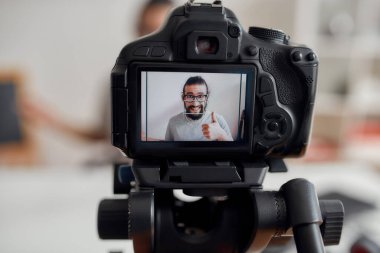 Genç erkek blogcu, video blogu ya da video blogu kaydederken kameraya doğru gösteriyor. Kamera ekranına odaklan