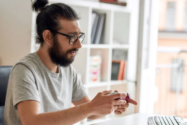 Αρσενικός blogger τεχνολογίας με γυαλιά που κοιτάζει το χειριστήριο παιχνιδιών joystick, κρατώντας το ενώ ηχογραφεί video blog ή vlog για νέα gadgets στο σπίτι — Φωτογραφία Αρχείου
