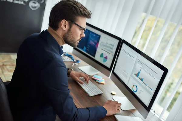 Elaboración del informe estadístico. Hombre de negocios o analista financiero enfocado que trabaja en la oficina moderna, mirando gráficos y gráficos en computadora y analizando datos estadísticos — Foto de Stock