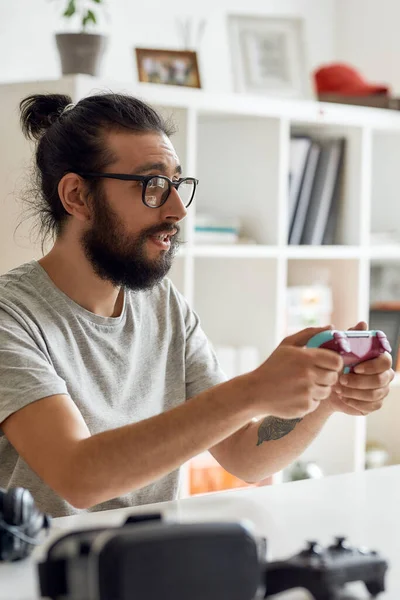 Hombre blogger de tecnología en gafas que sostiene joystick controlador de juego, mientras que la grabación de video blog o vlog sobre nuevos gadgets en casa —  Fotos de Stock