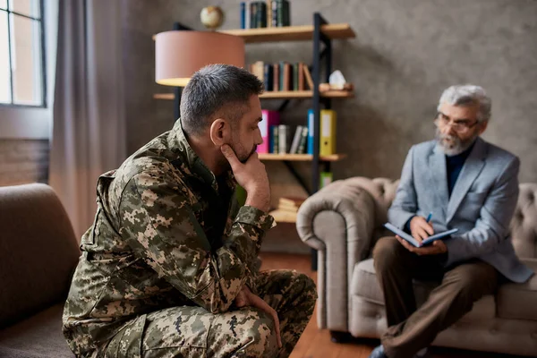 Stappen naar welzijn. Militaire man van middelbare leeftijd die communiceert met psycholoog, zittend op de bank tijdens therapie sessie. Soldaat lijdt aan depressie, psychologisch trauma. PTSS-concept — Stockfoto