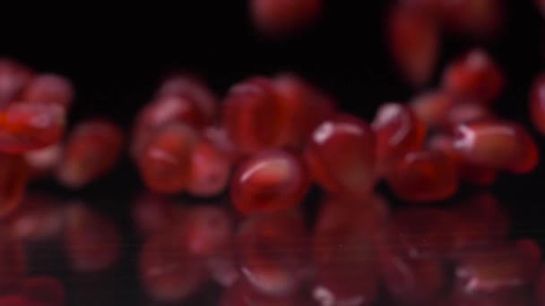 Vol van smaak. Super slow motion shot van granaatappel zaden vallen en rollen over zwarte achtergrond. Granaatappelkorrels sluiten 4K video af. Gezond eten, fruitconcept. — Stockvideo