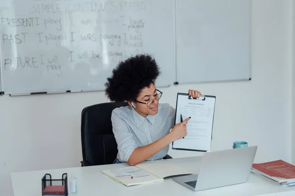 Non smettere mai di imparare. Giovane afro-americana insegnante di sesso femminile seduta sul posto di lavoro a casa e spiegare le regole della grammatica inglese mentre insegna online — Foto Stock