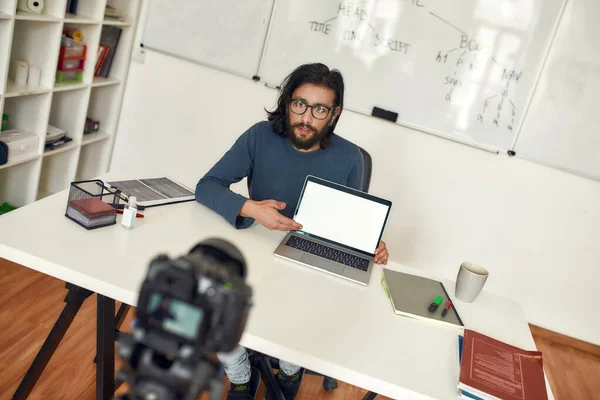 Programmering handledare, manlig lärare pekar på laptop tom skärm och förklara nytt tema, spela in video tutorial på professionell digital utrustning — Stockfoto