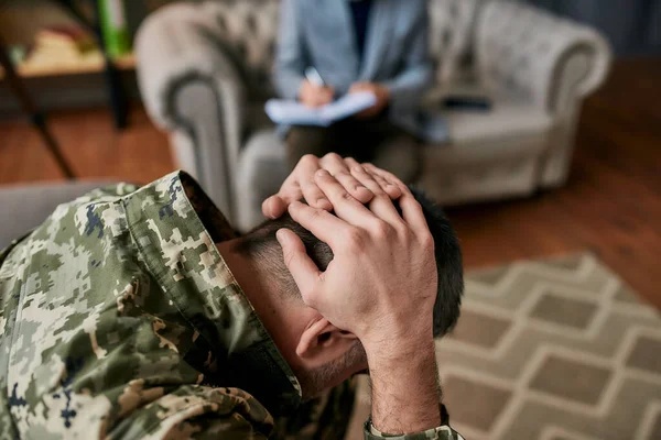 Pijnlijk leven. Close-up van een militair die zijn hoofd in pijn en depressie houdt tijdens een therapie sessie met een psycholoog. Soldaat lijdt aan psychologisch trauma. PTSS-concept — Stockfoto