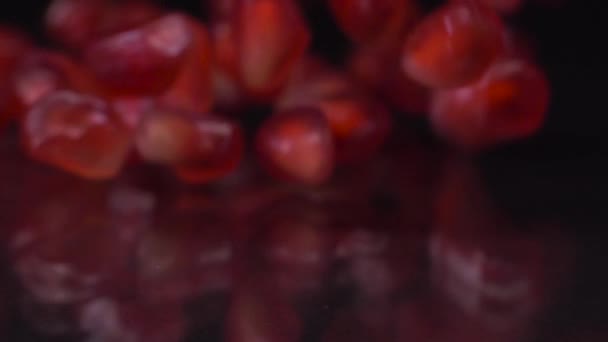 抗酸化物質の数が多い。ザクロの種の超スローモーションショットが落下し、黒の背景に転がります。ザクロ粒が4K動画を閉じます。健康的な食事、果物の概念. — ストック動画