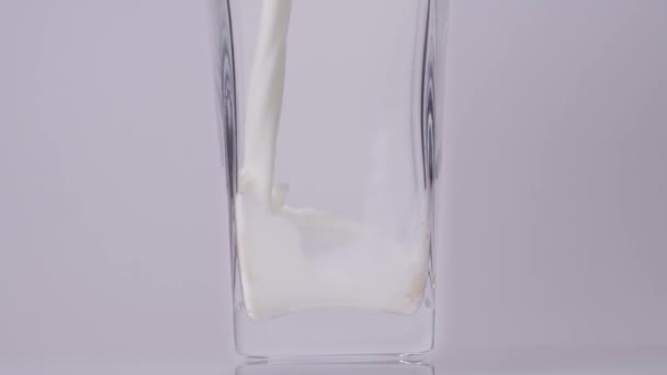 Mléko pro zdravou budoucnost. Super zpomalený záběr nalévání, cákání čerstvého mléka do průhledného skla na bílém pozadí. Zavřít. Koncept mléčných výrobků — Stock video