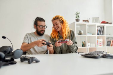 Kadın ve erkek oyun kumandalı joystick kullanıyor, tartışıyorlar. Genç erkek ve kadın teknoloji blogcusu evdeki yeni cihazlar hakkında video blogu veya video blogu kaydediyor