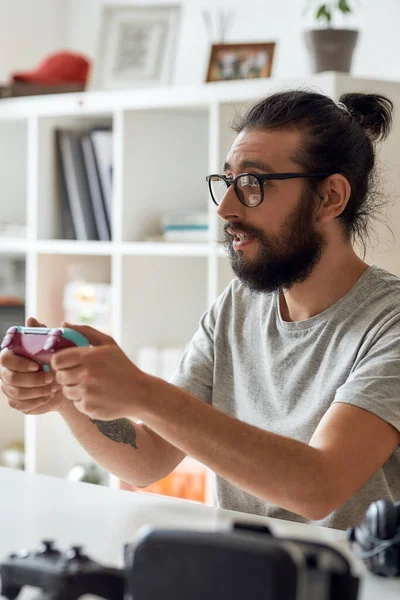 Blogger de tecnologia masculina em óculos segurando joystick controlador de jogo, durante a gravação de vídeo blog ou vlog sobre novos gadgets em casa — Fotografia de Stock