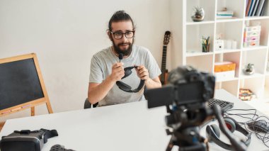 Erkek teknoloji blogcusu elinde kulaklık tutarken video blogu veya video blogu kaydediyor.