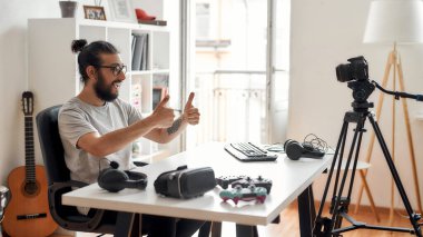 Erkek teknoloji blogcusu başparmaklarını gösteriyor, video blogu veya video blogu kaydediyor.
