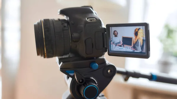 Couple of bloggers, young man and woman in headphones looking at each other while talking, recording conversation, interview for video blog. Focus on camera screen — Stock Photo, Image