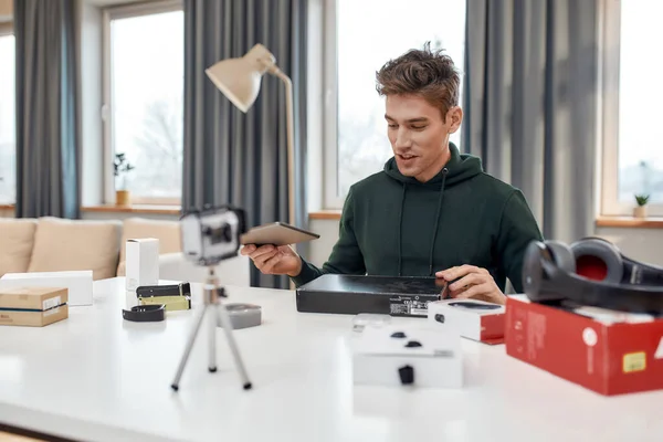 Joven blogger de tecnología masculina grabación de video blog o vlog sobre la nueva tableta PC y otros aparatos en el estudio en casa. Blogging, Trabajo desde el hogar concepto —  Fotos de Stock