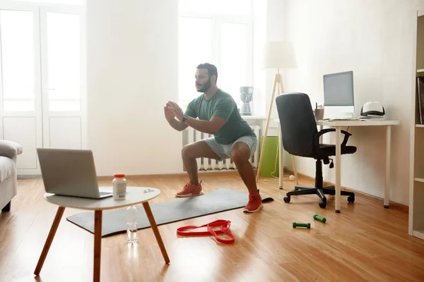 Продовжуй. Повнометражний знімок молодого активного чоловіка, який дивиться онлайн відео тренувань на ноутбуці, тренувань під час ранкового тренування вдома. Спорт, здоровий спосіб життя — стокове фото