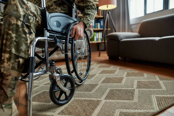 Gehandicapten. Gehaktfoto van een gehandicapte militair met camouflage in een rolstoel tijdens een therapiesessie in de woonkamer. PTSS-concept — Stockfoto