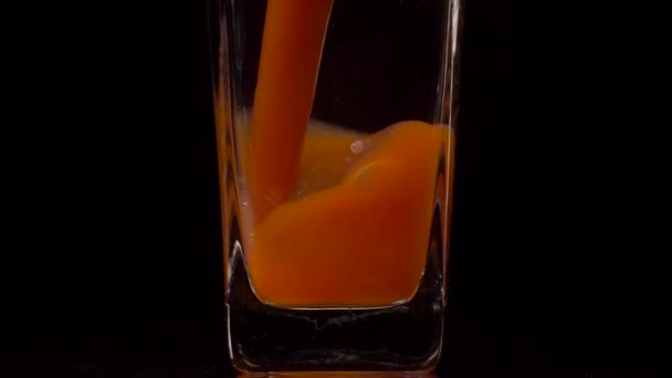 Gerçek meyve suyu. Şeffaf bir bardağa siyah arkaplana domates suyu dökerken çekilen süper yavaş çekim. Kapatın. Sağlıklı içecek, vitamin konsepti — Stok video
