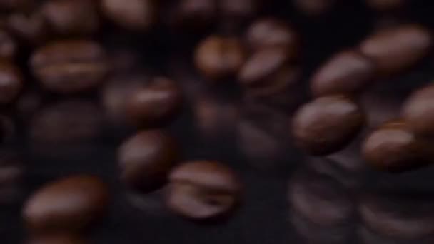 Roosteren. Slow motion shot van verse geroosterde bruine koffiebonen rollen, vallen op houten tafel, donkere achtergrond. Koffie granen close-up 4K video — Stockvideo