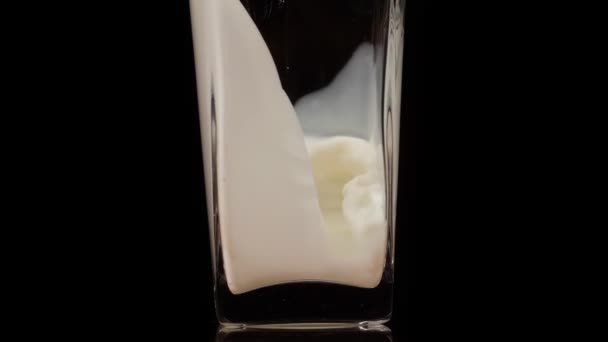 De smaak van de natuur. Super slow motion shot van het gieten van verse melk in een transparant glas tegen zwarte achtergrond. Sluit maar af. Zuivelproductconcept — Stockvideo