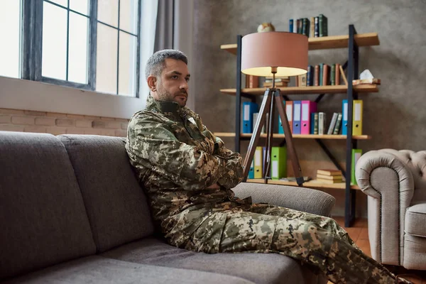 Bevrijd de wereld van pijn. Trieste militaire man van middelbare leeftijd die wegkijkt, zittend op de bank tijdens therapiesessie. Soldaat lijdt aan depressie, psychologisch trauma. PTSS-concept — Stockfoto