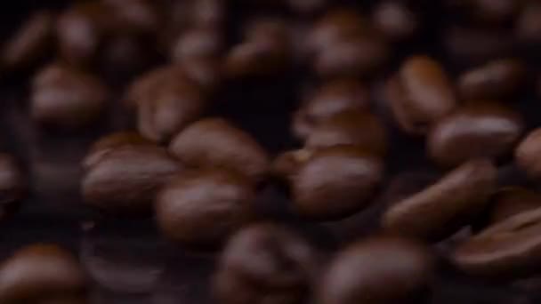 Jedinečné ingredience. Zpomalený záběr prémiových čerstvě pražených hnědých kávových zrn, padajících na dřevěný stůl, tmavé pozadí. Kávová zrna zavřít 4K video — Stock video