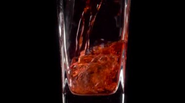 Moda Doğa İçeceği. Şeffaf bir bardağa siyah zemin üzerine nar suyu dökerken süper yavaş çekim. Kapatın. Sağlıklı içecek, vitaminler, meyve konsepti