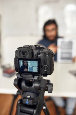 Video blogu kaydediliyor. Genç adam internette öğretmenlik yapıyor, evde çalışırken yeni konuları anlatıyor. Kameraya odaklan, profesyonel dijital ekipman