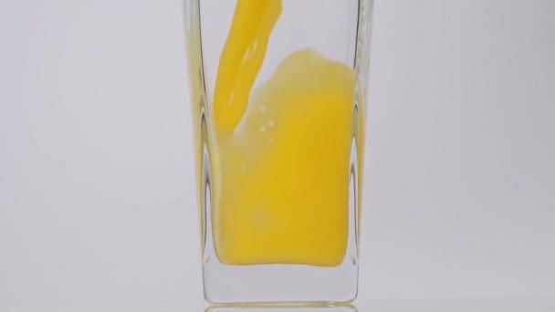 Jugo nuevo. Super toma en cámara lenta de verter jugo de naranja en un vaso transparente sobre fondo blanco. De cerca. Bebida saludable, vitaminas, concepto de frutas — Vídeo de stock