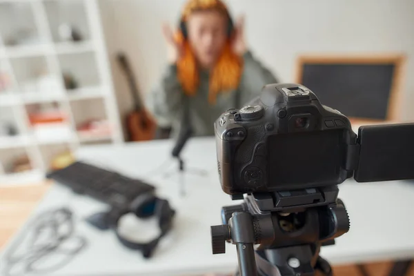 Γυναίκα blogger τεχνολογίας με dreadlocks καταγραφή βίντεο αναθεώρηση των νέων gadgets χρησιμοποιώντας κάμερα στο σπίτι. Εστίαση στην κάμερα — Φωτογραφία Αρχείου