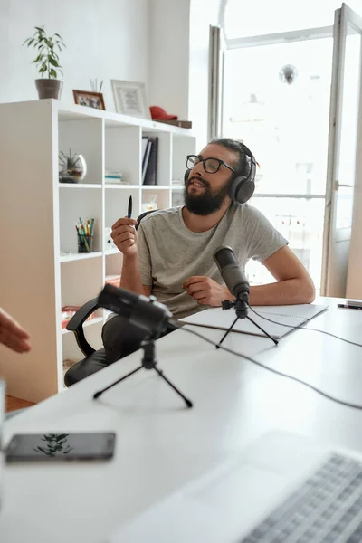Мужчина блогер, мужчина в наушниках, слушает собеседника во время разговора, записывает разговор, интервью для видеоблога — стоковое фото