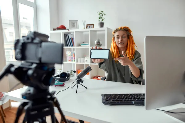 Regarde-moi ça. Blogueur de technologie féminine avec dreadlocks regardant la caméra, montrant smartphone avec écran vide tout en enregistrant blog vidéo ou vlog dans la journée — Photo