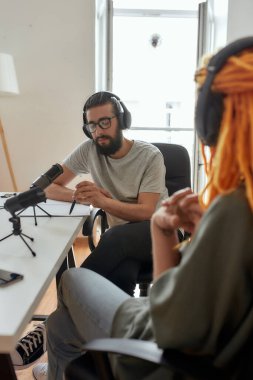 Erkek blogcu, kulaklıklı adam düşünceli görünüyor, konuşmayı kaydederken konuşmacıyı dinliyor, video günlüğü için röportaj yapıyor.